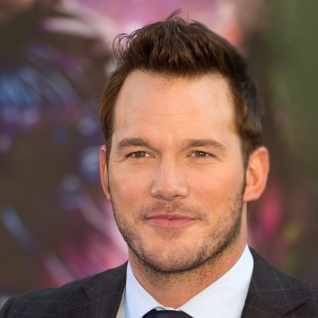 Chris Pratt in a black suit poses for a picture.